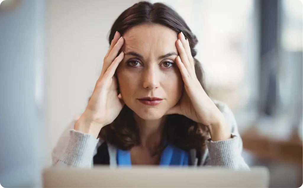 Stressed female executive holding her head, illustrating the need for trauma treatment for professionals.