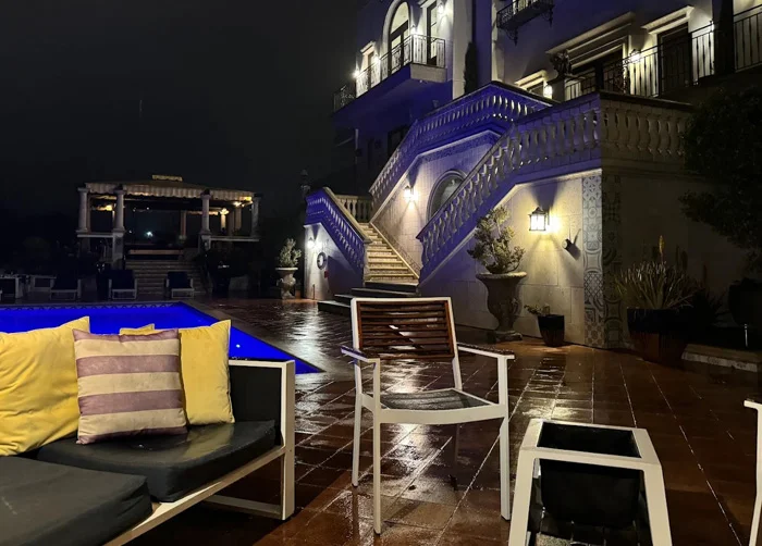 An illuminated outdoor courtyard at a luxury rehab center in Los Angeles featuring a blue-lit pool, comfortable lounge seating, and elegant Mediterranean architecture at night.