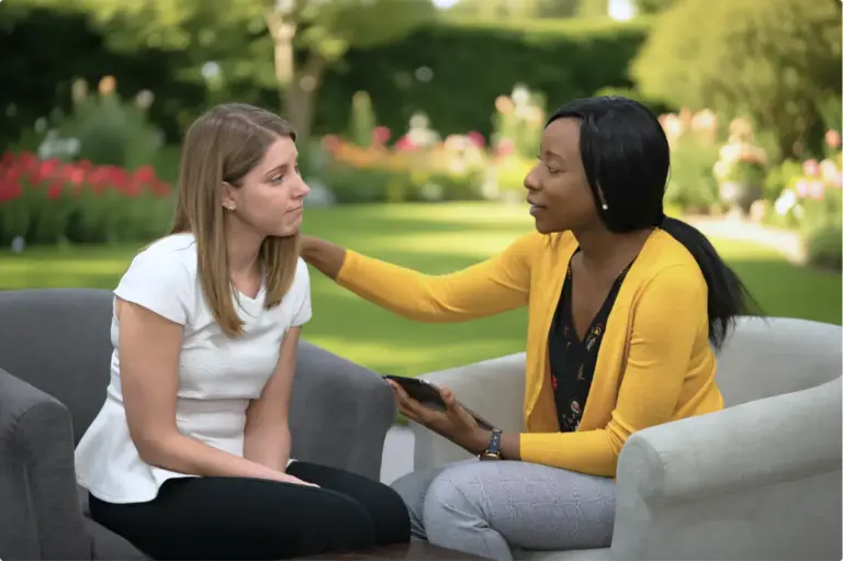 Therapist providing holistic healing for addiction support to a woman in an outdoor garden setting.