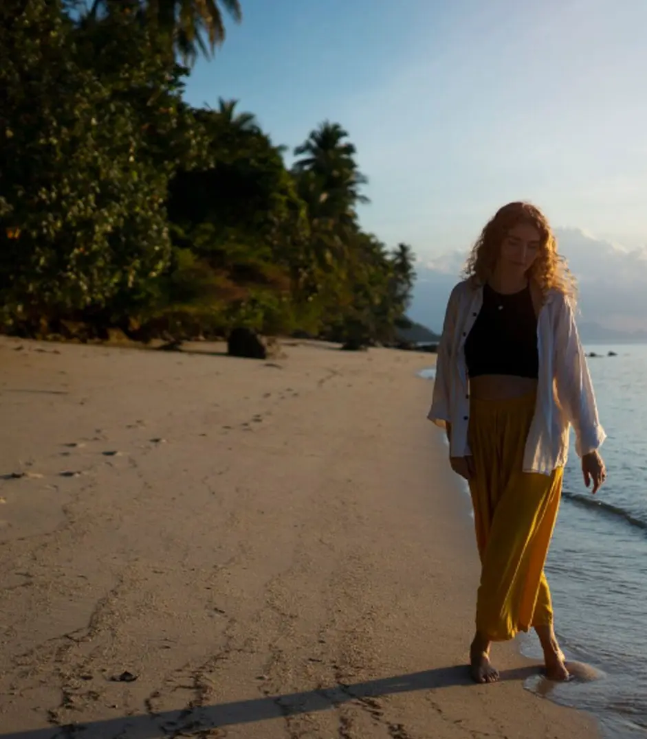 Individual walking along the beach during ocean therapy session for relaxation, mindfulness, and emotional healing