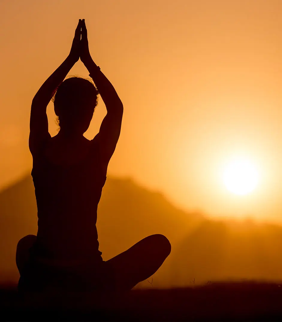 Individual practicing sunset yoga for mindfulness, stress reduction, and holistic wellness during recovery