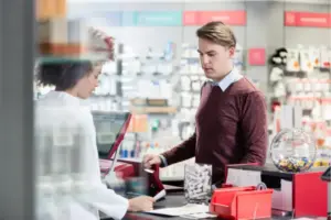Man purchasing over-the-counter products at a pharmacy counter related to gas station drugs and substance misuse risks among high performers.