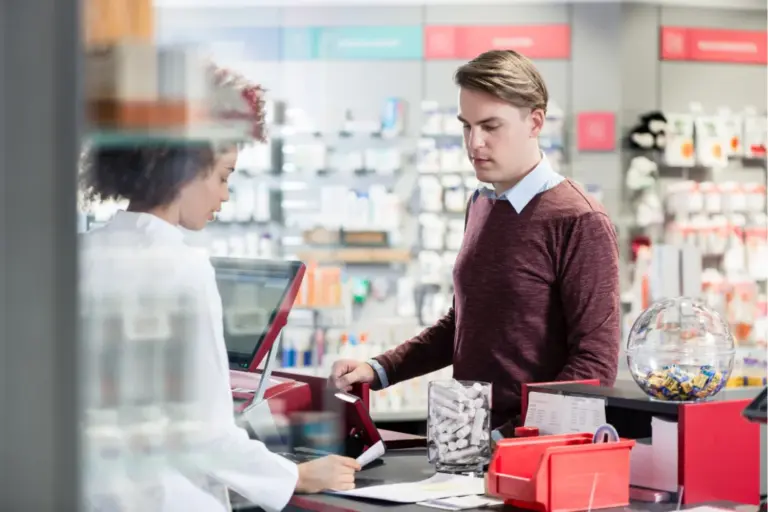 Man purchasing over-the-counter products at a pharmacy counter related to gas station drugs and substance misuse risks among high performers.
