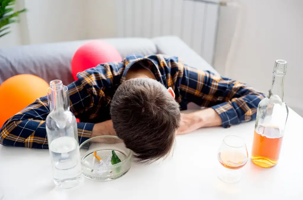 Person near alcohol bottles while taking meloxicam, illustrating the risks of mixing meloxicam and alcohol