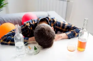 Person near alcohol bottles while taking meloxicam, illustrating the risks of mixing meloxicam and alcohol