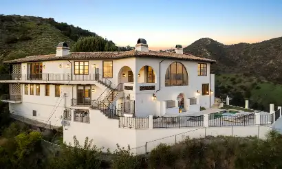 Wattles luxury rehab residence in the Los Angeles hills featuring Mediterranean-style architecture, arched windows, balconies, mountain views, and a private pool.